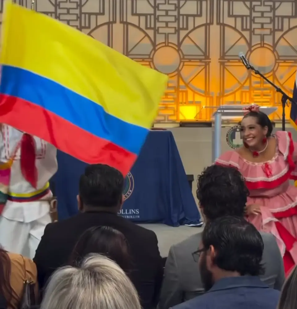 Bailarín ondeando la bandera de Colombia junto a una bailarina con pollera rosada en City Hall de Houston
